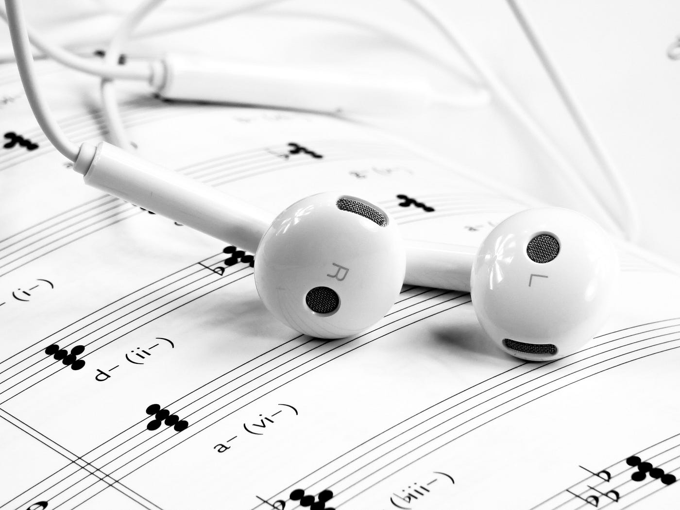 Sheet music with white earbuds laying on top.