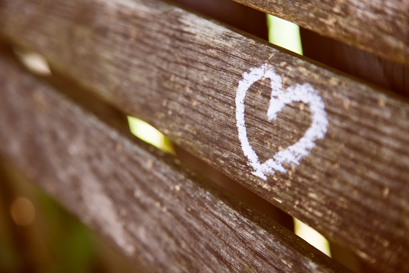 zoom in wooden bench with a white chalked heart etched onto a board