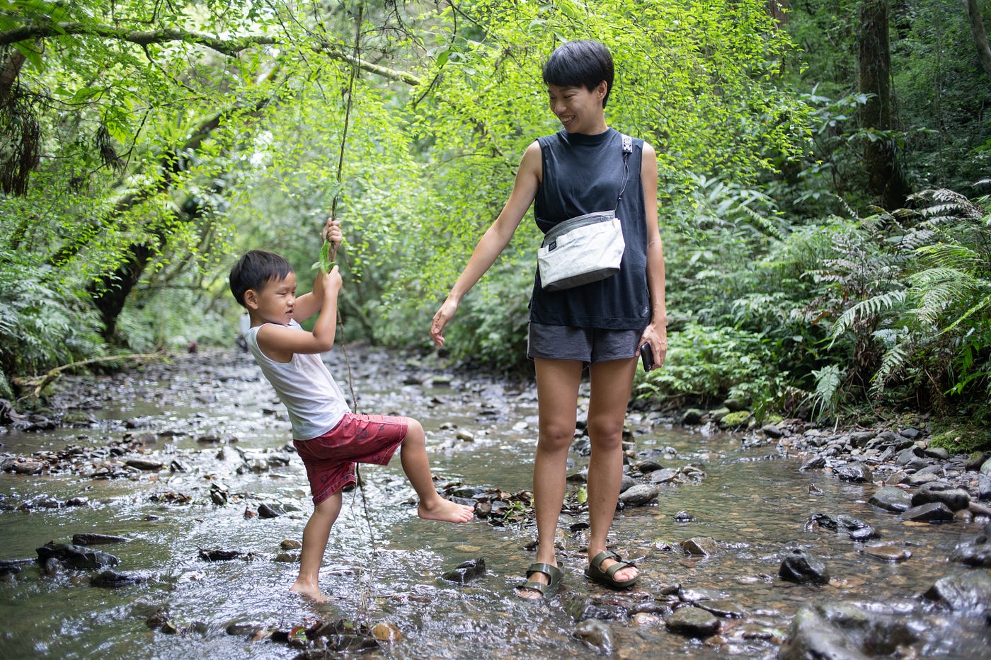 a lady wear a sling bag walk in the river