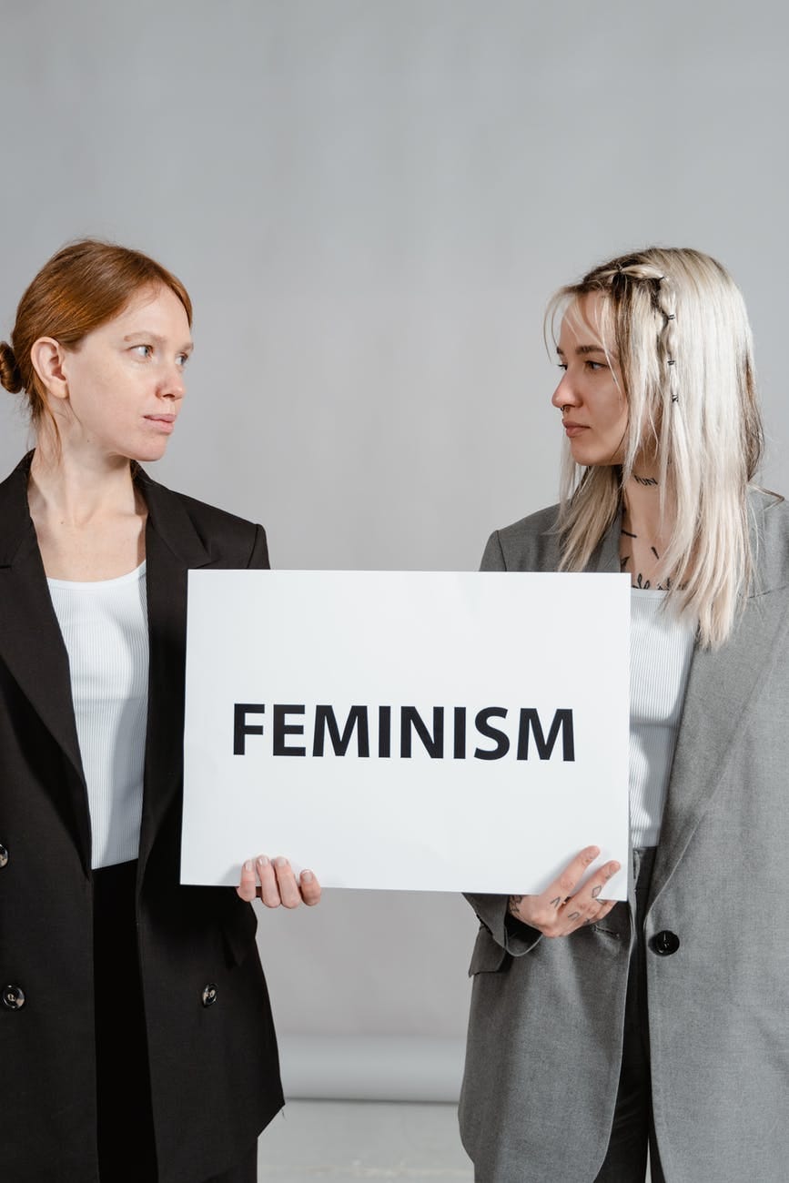 Two white women holding a feminism sign.