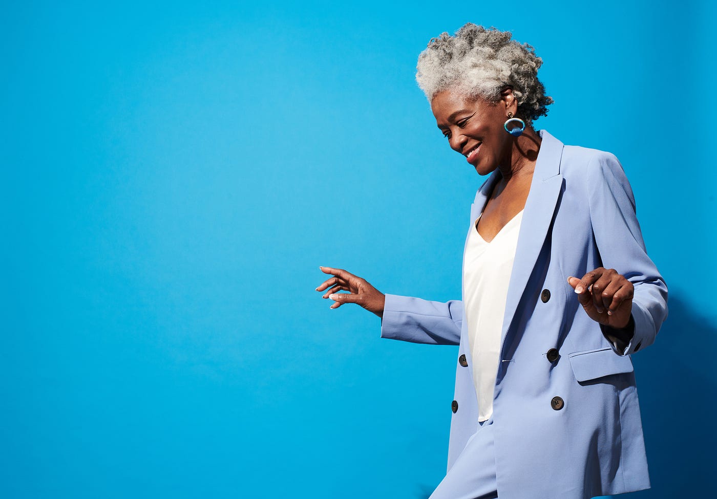 Confident, smiling older Black woman in a powder blue suit against a sky blue background.