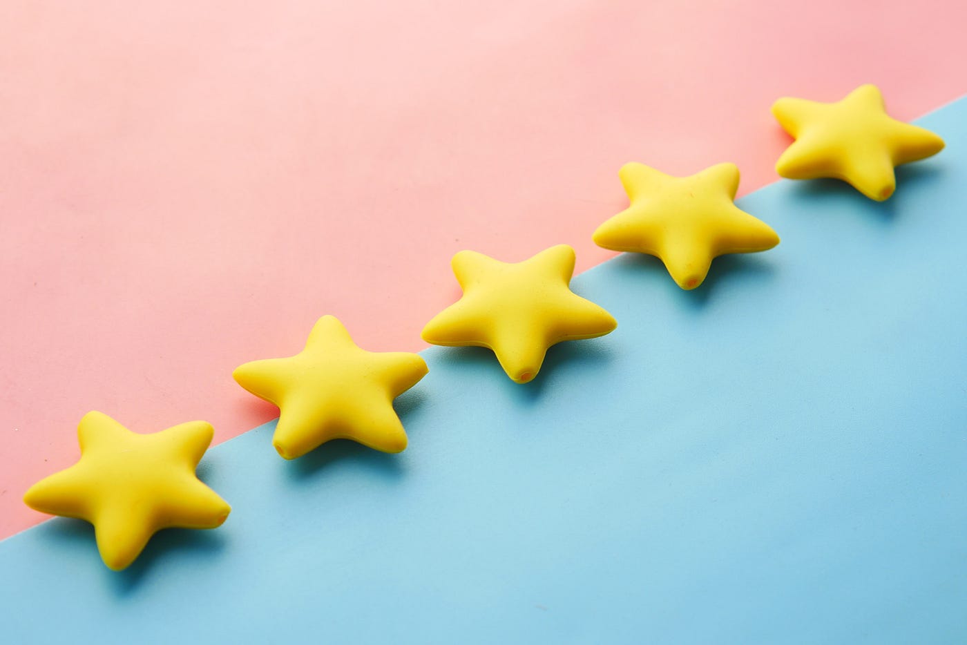 five yellow star shaped cookies lined up between pink and blue background