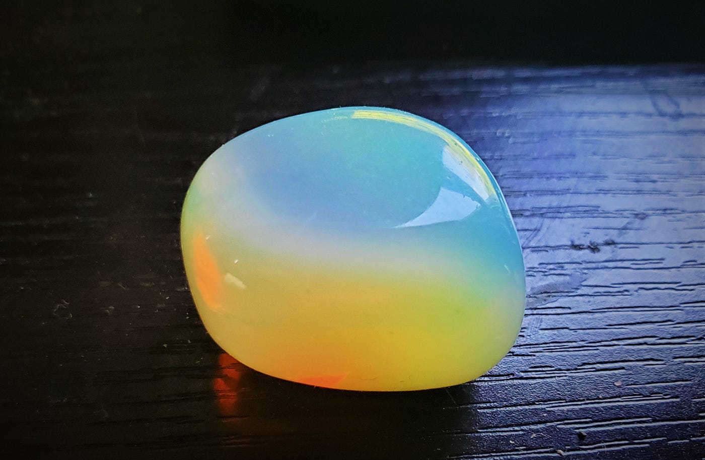 Close-up of a tumbled opal with light hitting it