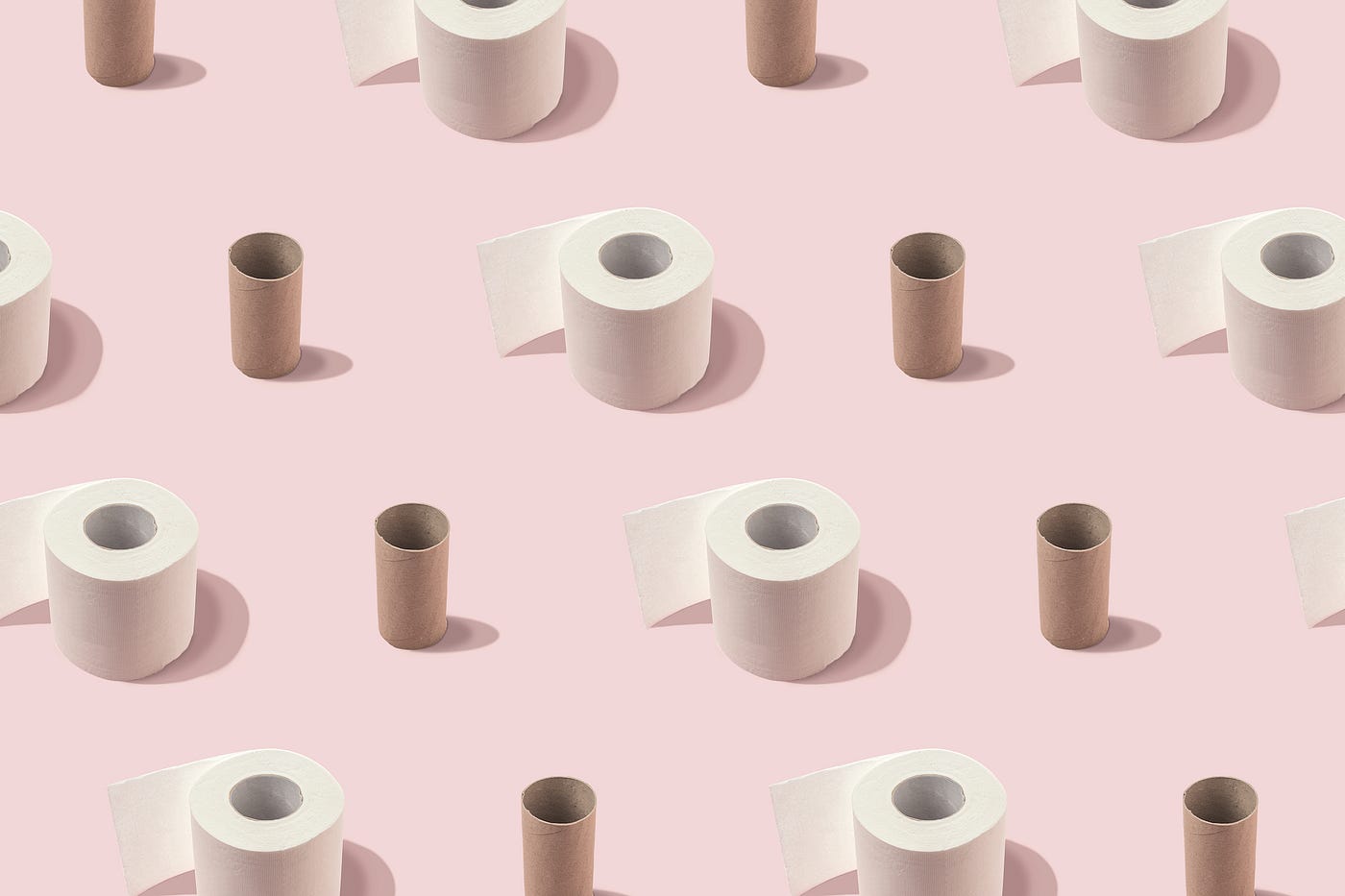Alternating rows of toilet paper rolls and cardboard toilet paper tubes on a pink surface.