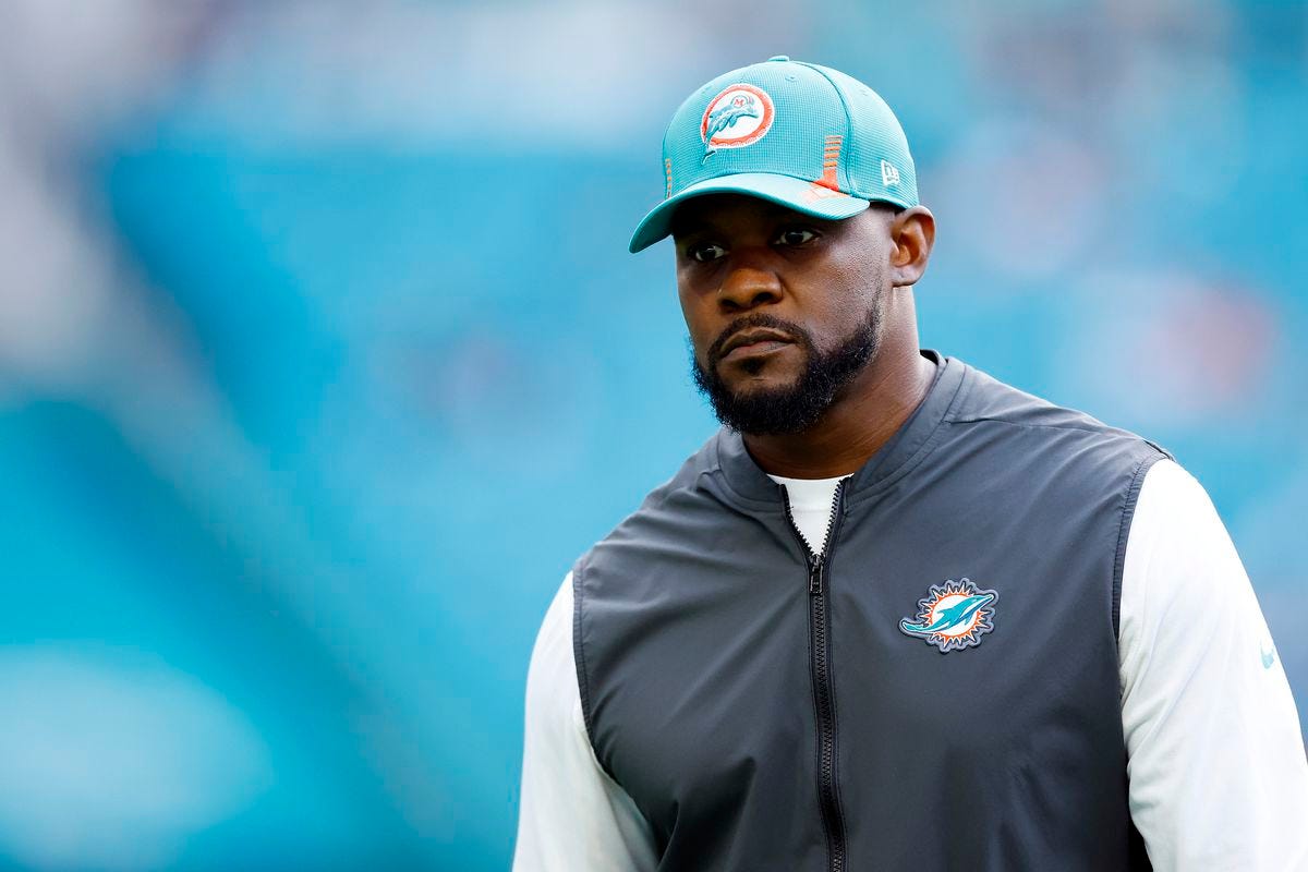 Brian Flores, former coach of the Miami Dolphins, standing on the sidelines before a game.