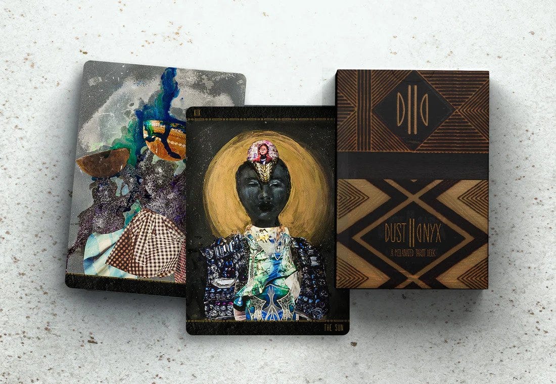The travel edition of the Dust II Onyx tarot deck sits on a table with bright lights and cards from the deck on display.