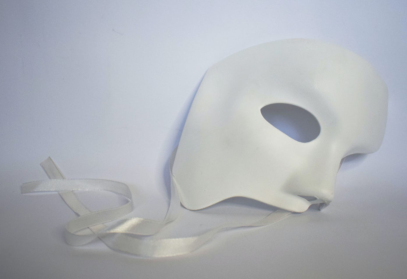 An image of a white ghost mask in a white background signifying the loss of identity.