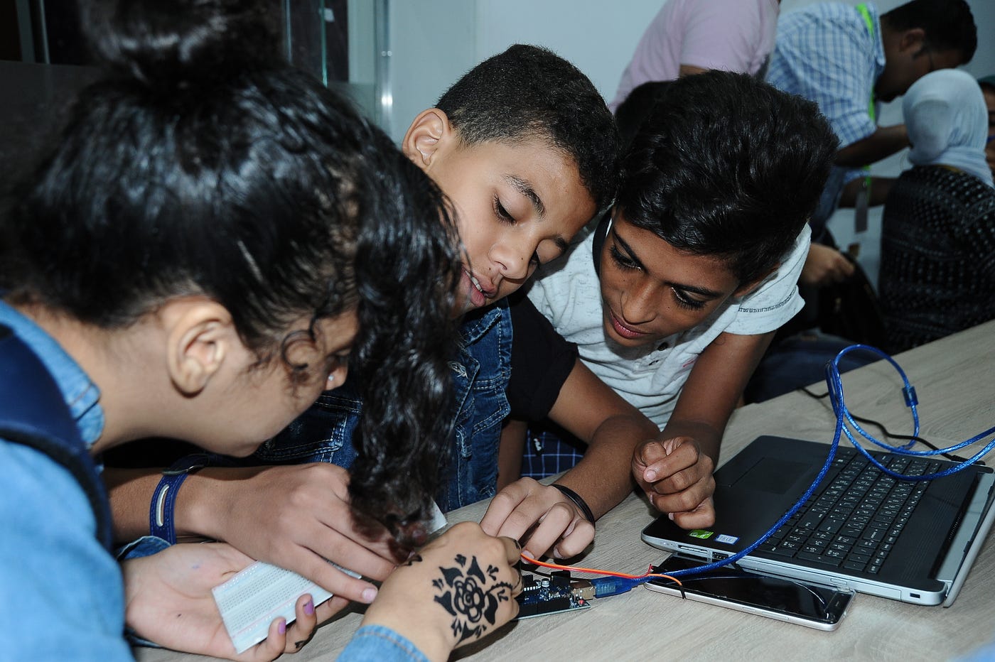 Three students work on a small circuit board.