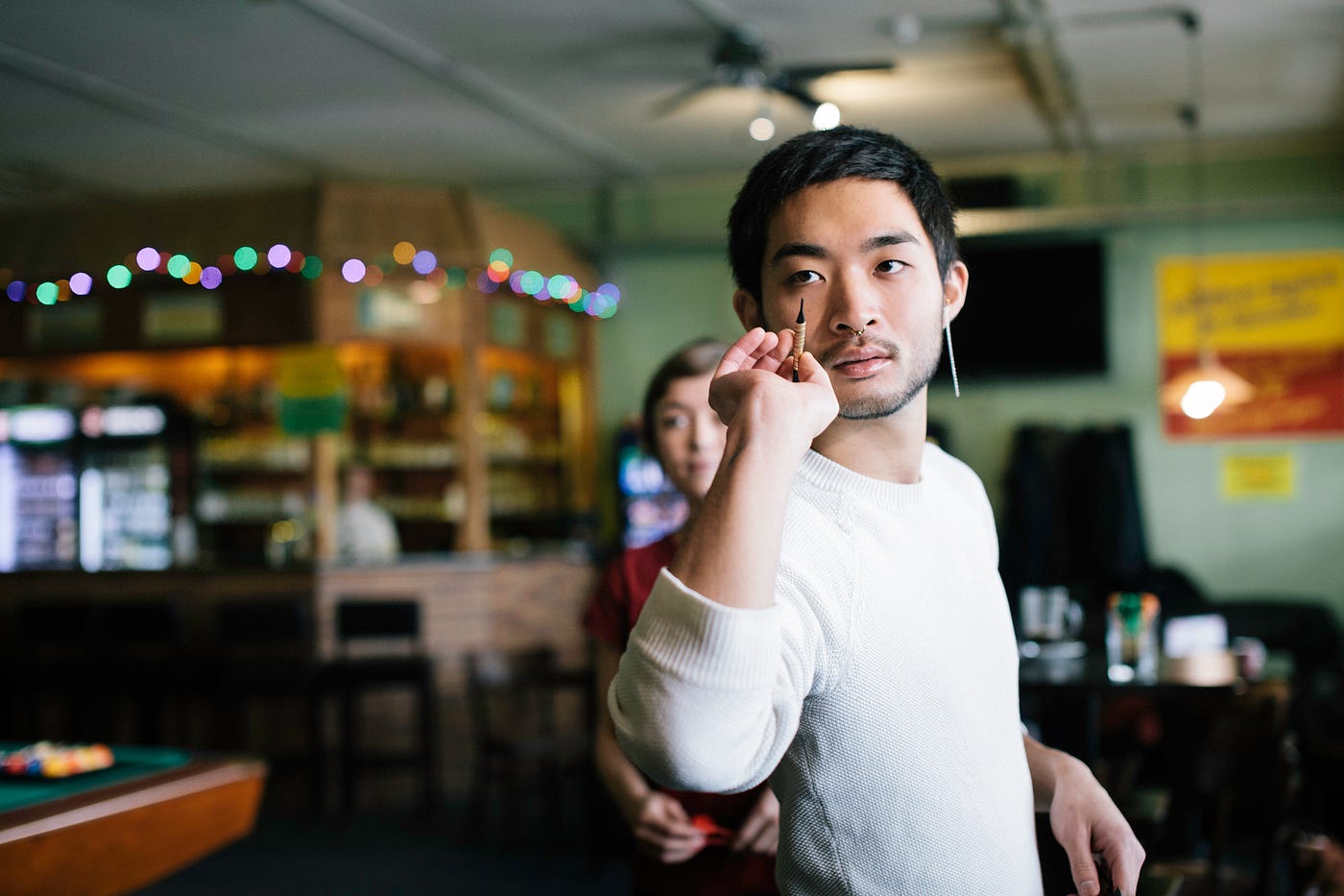 A man prepares to throw a dart with a focused expression.