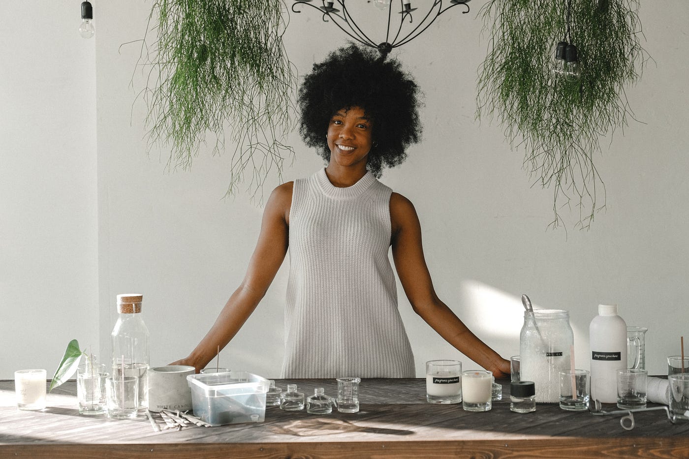 Delighted Black woman standing at table in workshop for making candles