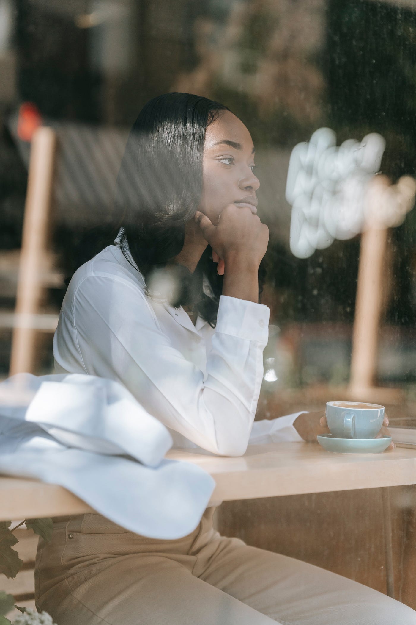 Black woman sitting alone lost in her thoughts drinking coffee
