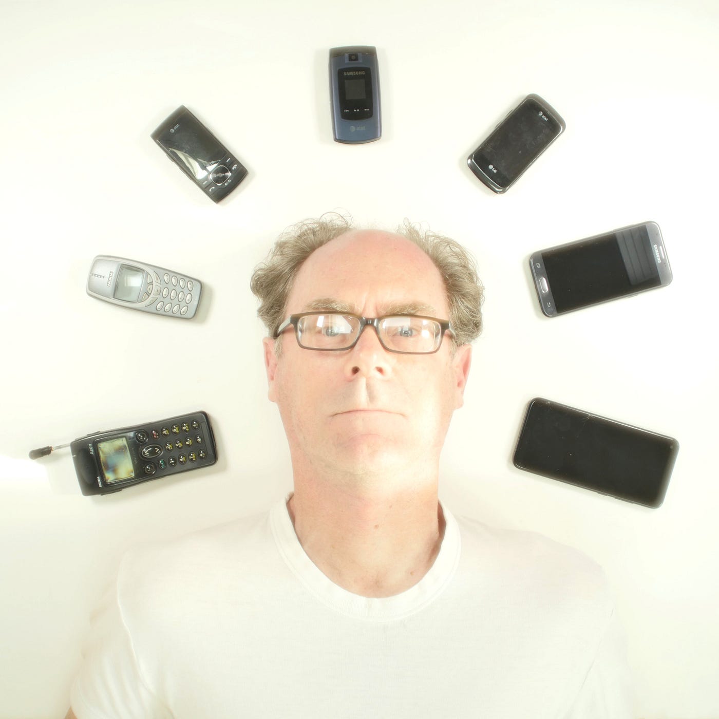 Self portrait of my head surrounded by all the cell phones that I’ve owned