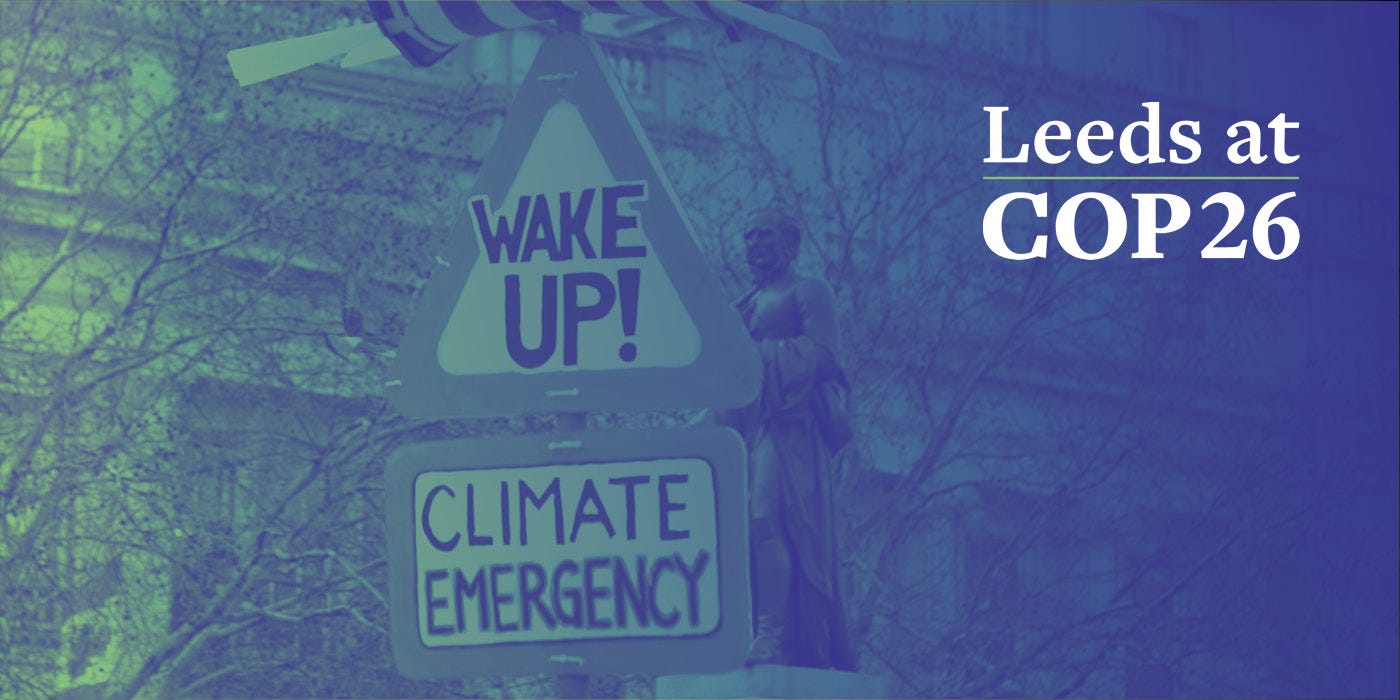 Climate protest sign saying Wake Up! Climate Emergency. Image overlaid in the corner by the text Leeds at COP26.