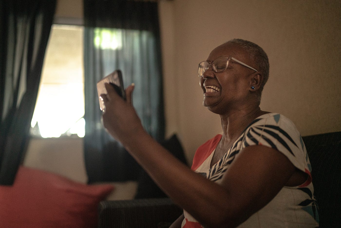 Elderly Black woman smiling while on a video call at home.