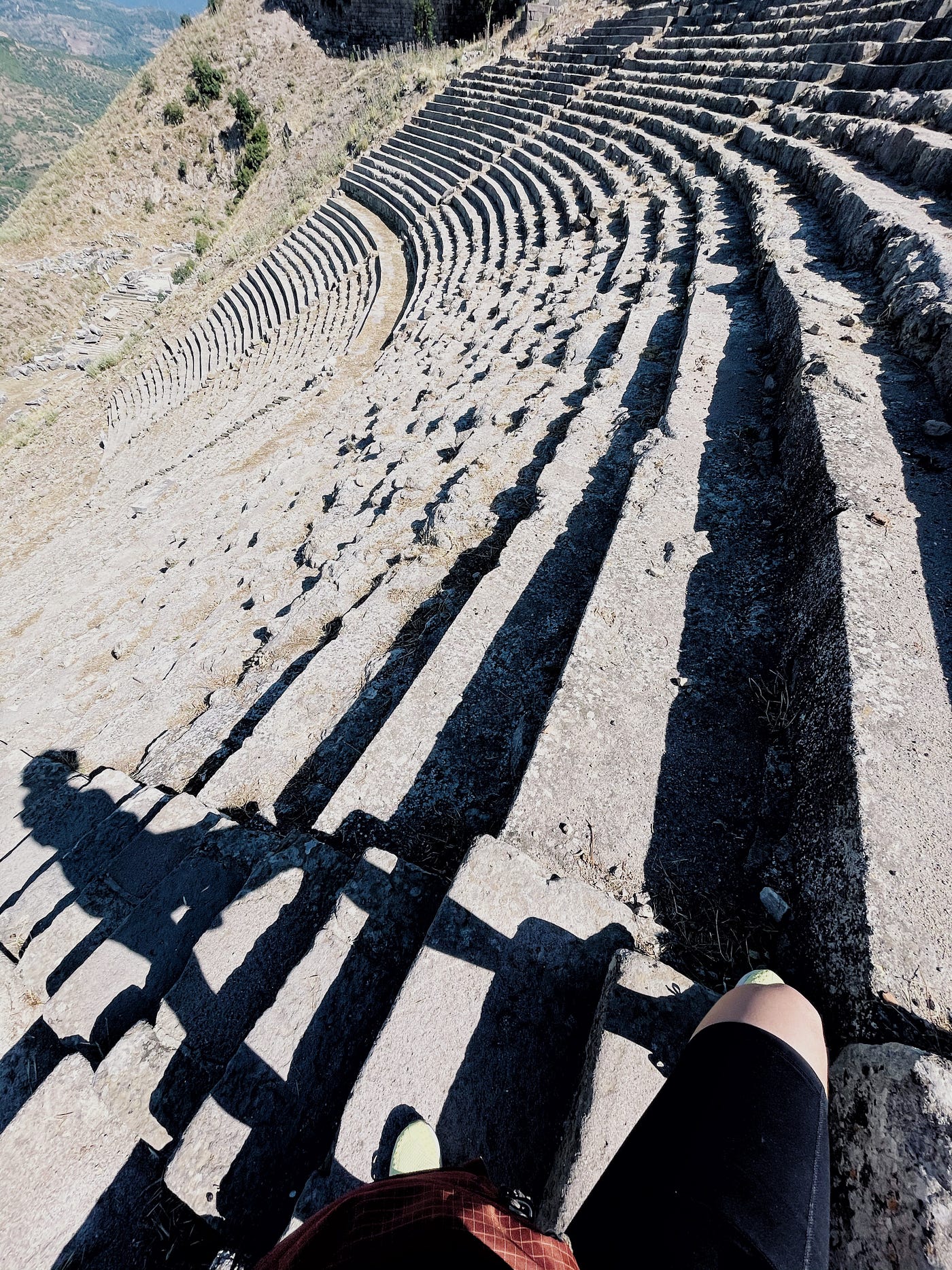 Woman’s shadow over the steps of a steep antique theater in the Aegean.