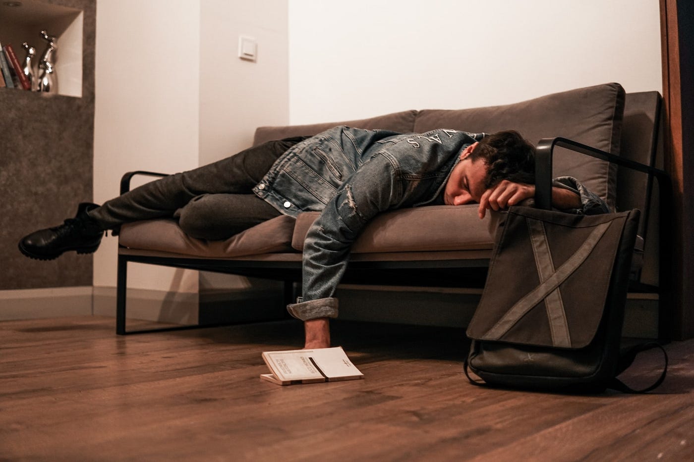 Man sleeping on sofa with book fallen to the floor