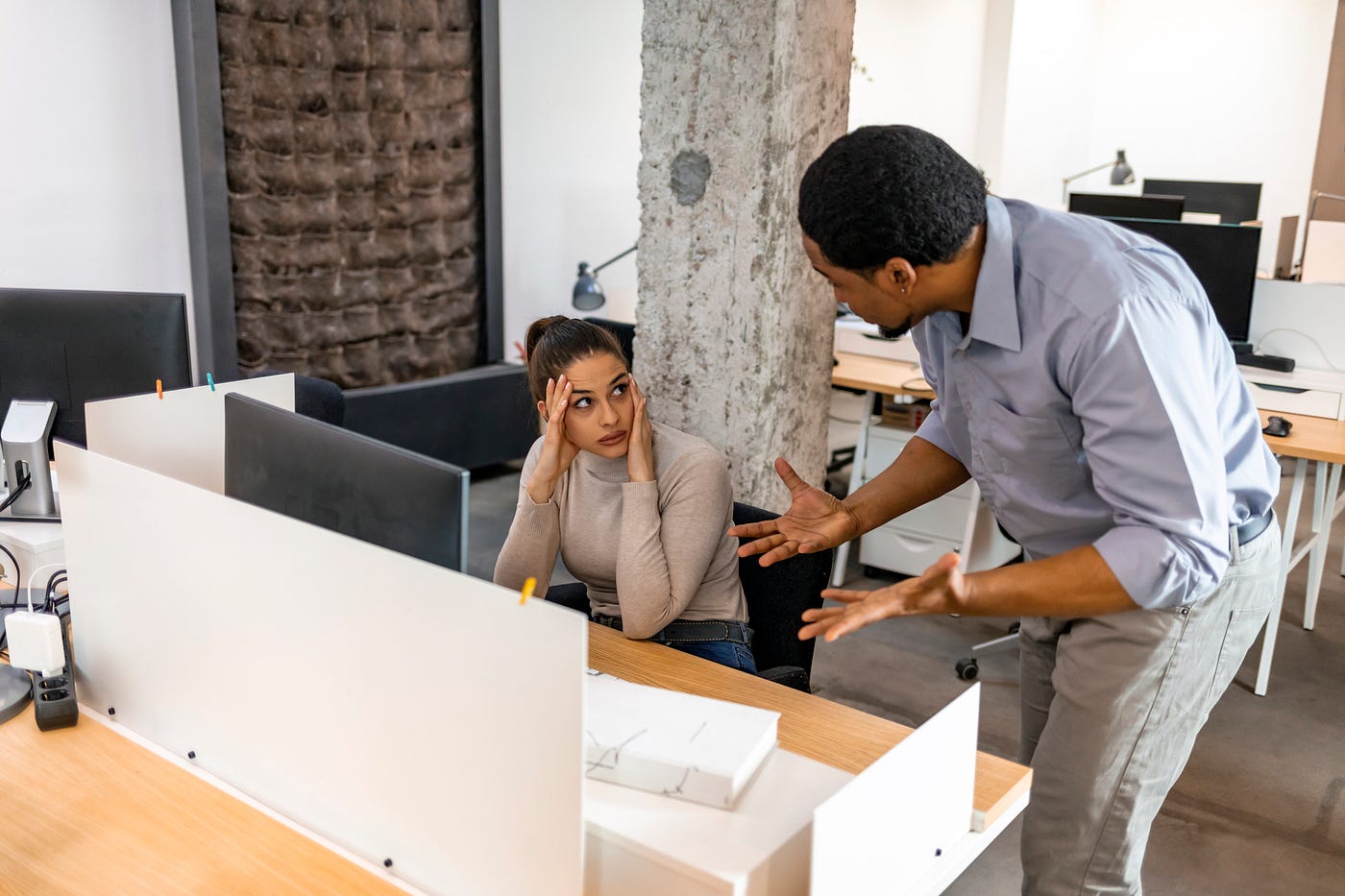 Stressed female employee with a frustrated male boss at work.