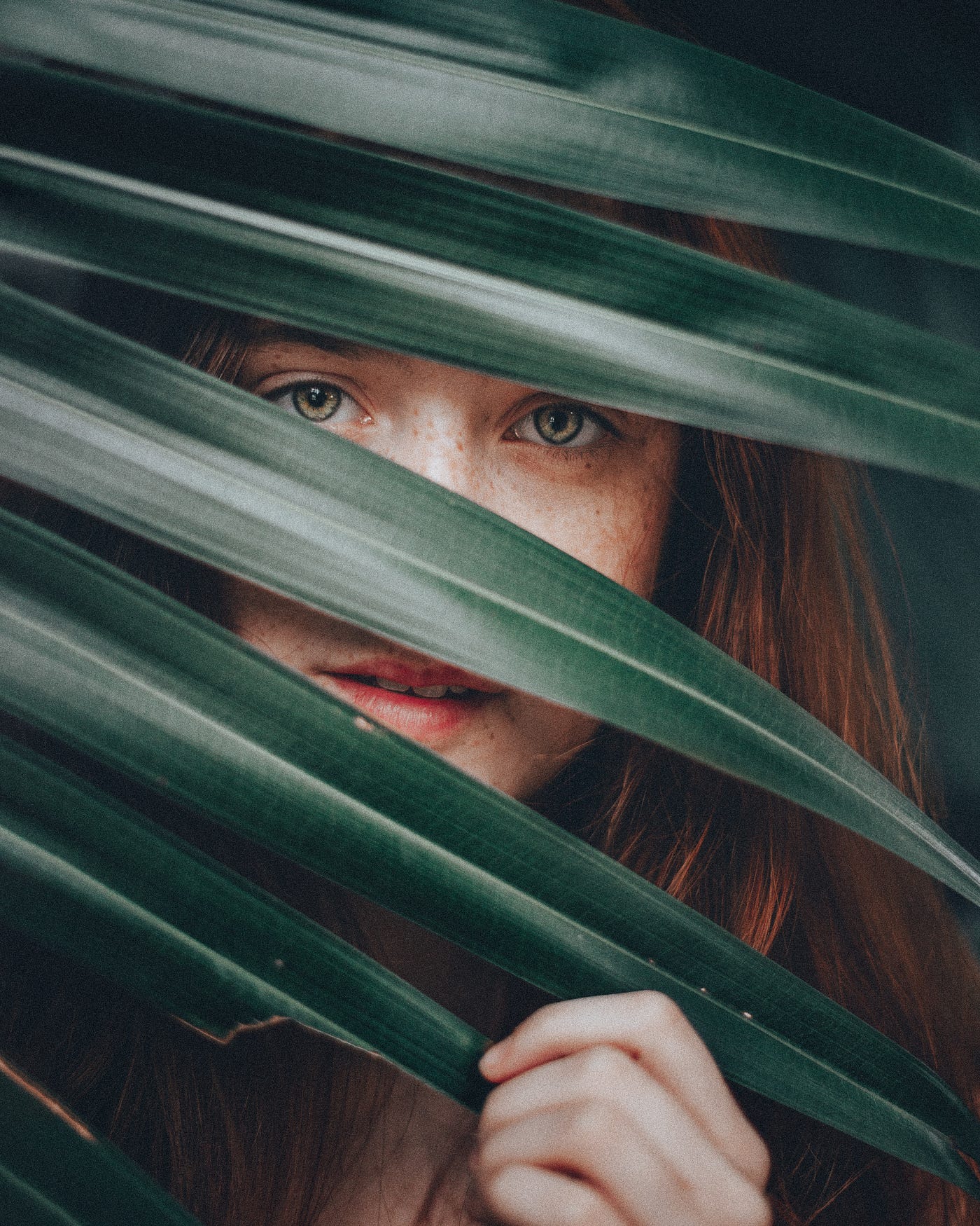 Shy girl looking through palm fronds