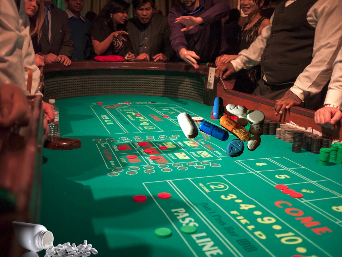 A craps table surrounded by excited gamblers; amid the casino chips are various pharma tablets, some spilling out of a pill bottle. Image: Chris Martin (modified) https://www.flickr.com/photos/cjmartin/11331819423 CC BY 2.0: https://creativecommons.org/licenses/by/2.0/ Christine Dela Cerna (modified) https://commons.wikimedia.org/wiki/File:Various_pills.JPG CC BY-SA 3.0: https://creativecommons.org/licenses/by-sa/3.0/deed.en