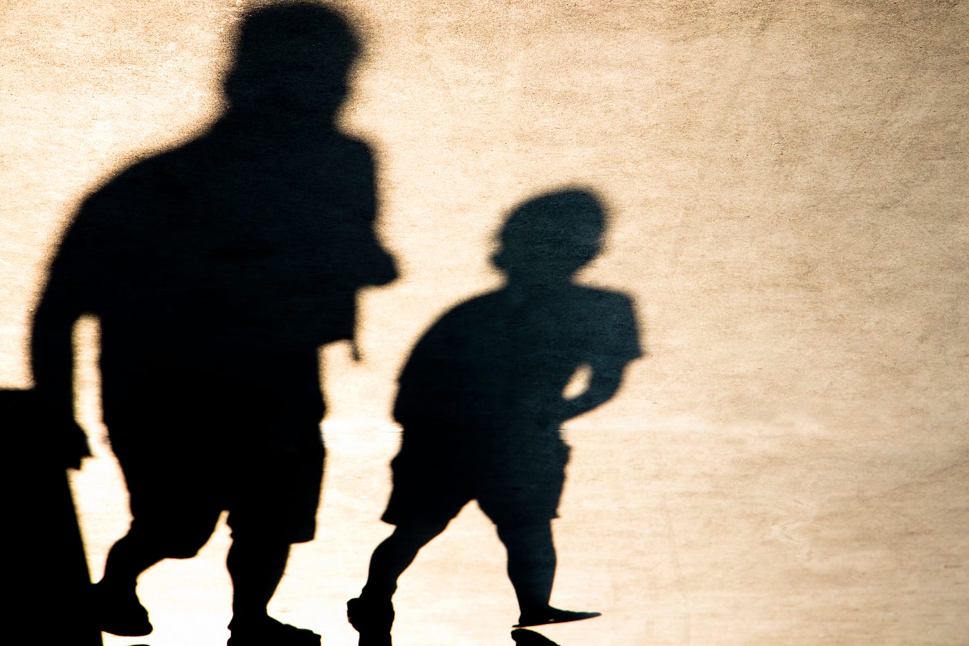 Shadows of an older person and younger person walking together.
