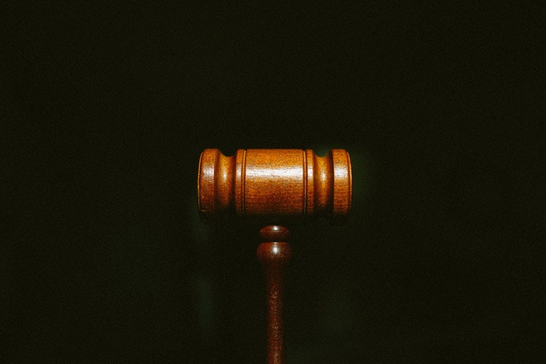 A judge’s wooden gavel against a dark background.