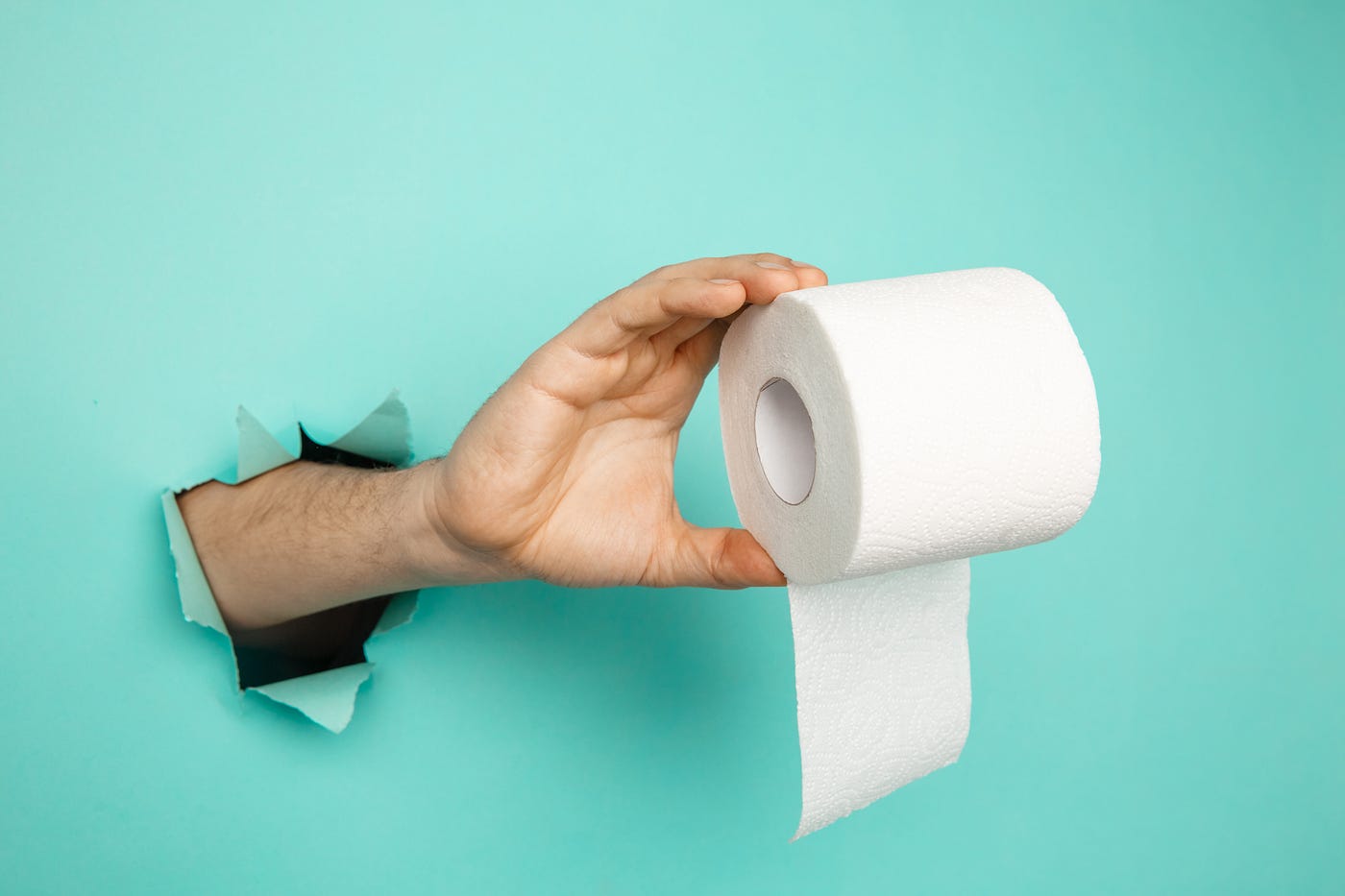 man-s-hand-holding-roll-toilet-paper-from-blue-torn-background — Un Swede