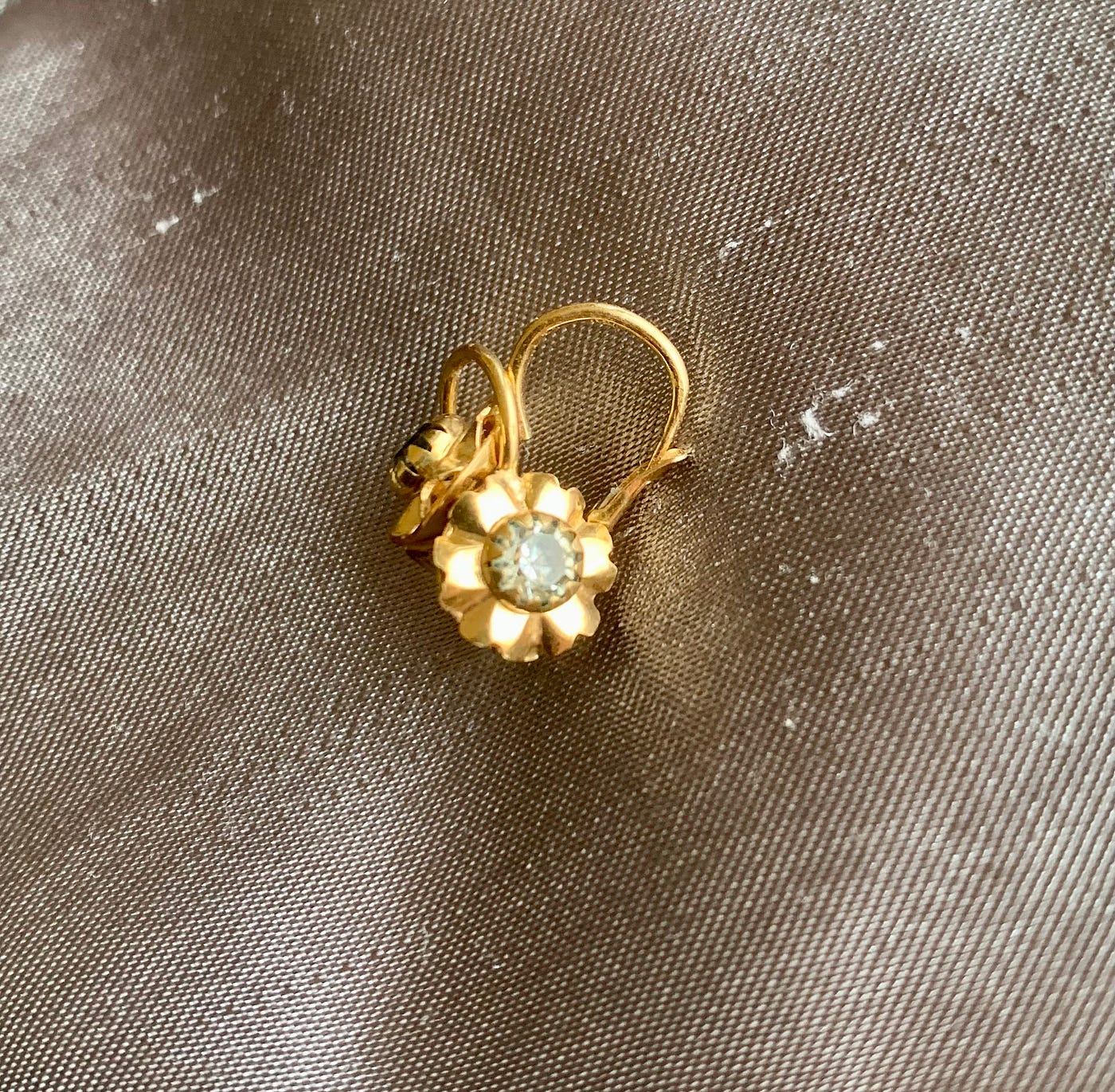 Gold earrings in the shape of sunflowers with a diamond in the middle.