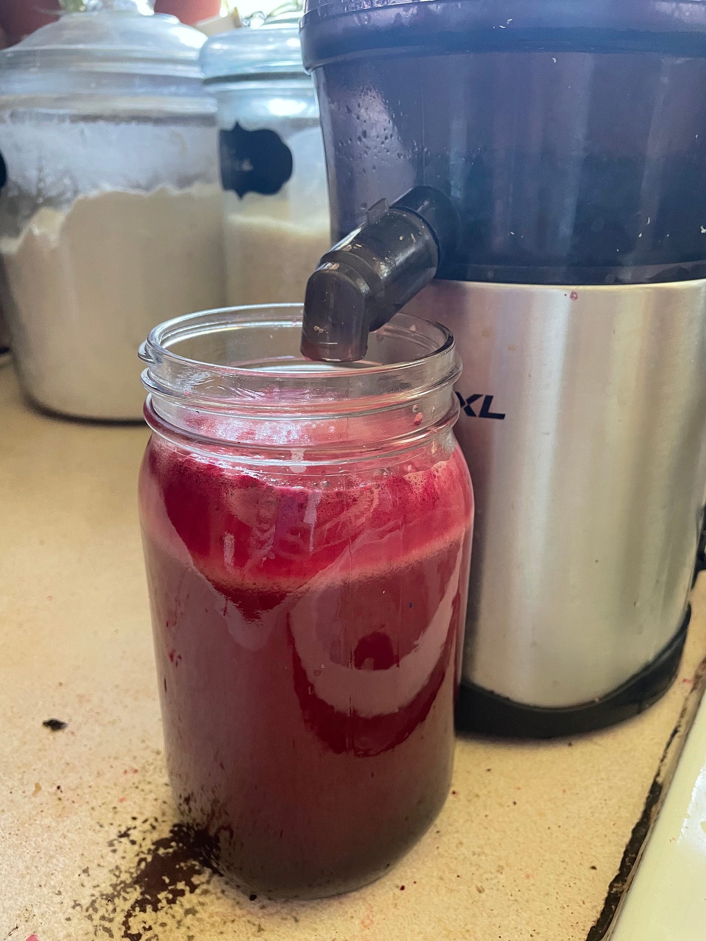 A close up view of juice coming out of the juicer into a glass.