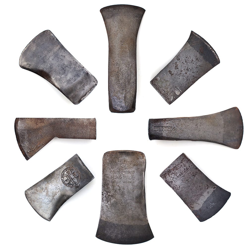 A detail of 8 axe heads without handles showing unique makers marks in the steel.