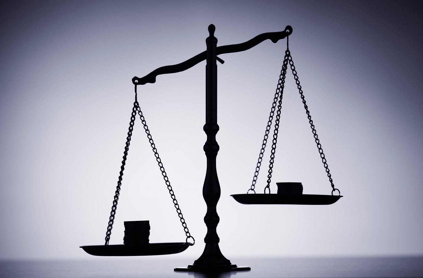 Silhouette of a scale with gold coins, unevenly tipped to the left scale.