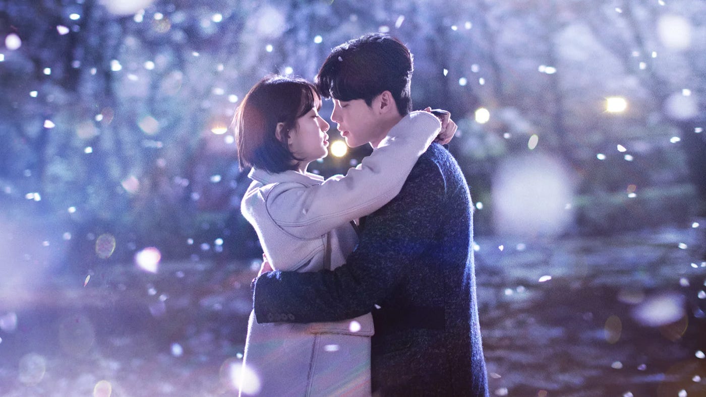 A korean couple about to kiss underneath a shower of cherry blossoms