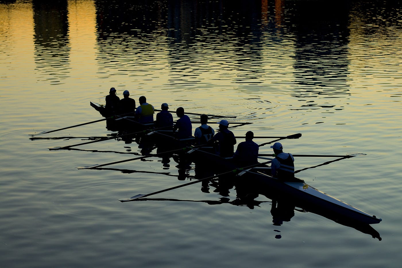 An image of a rowing team’s silhouettes against the water.