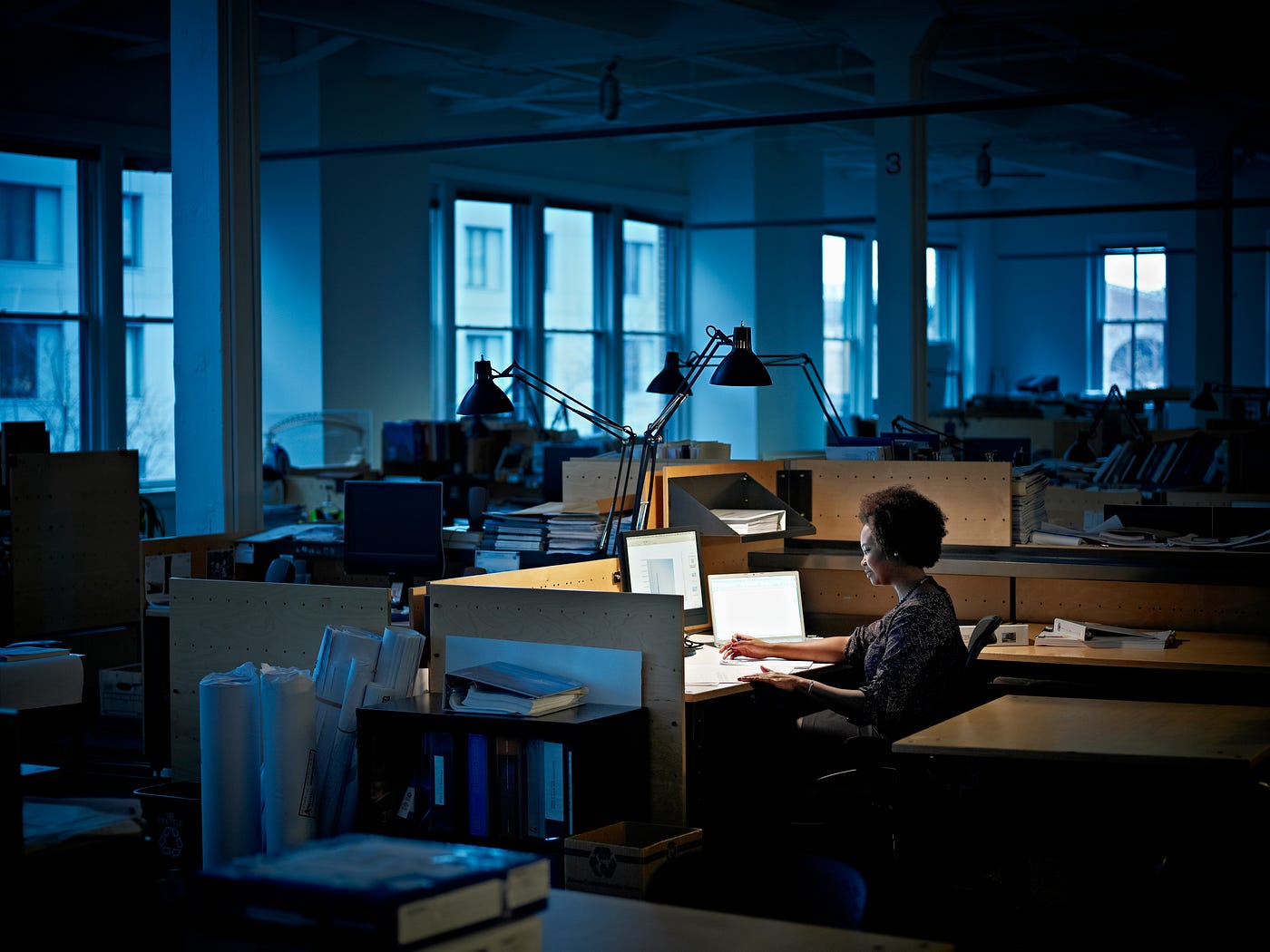 A black woman working alone in a dark office