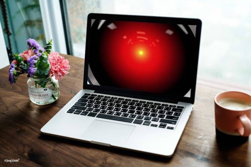 A laptop on a home desk, its screen filled with the red eye of HAL9000 from 2001: A Space Odyssey.