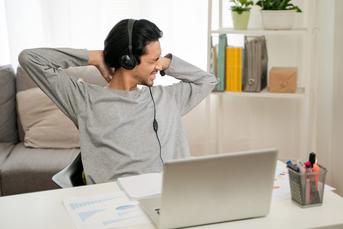 A young man experiencing stress after a video conference on his laptop, working from home.