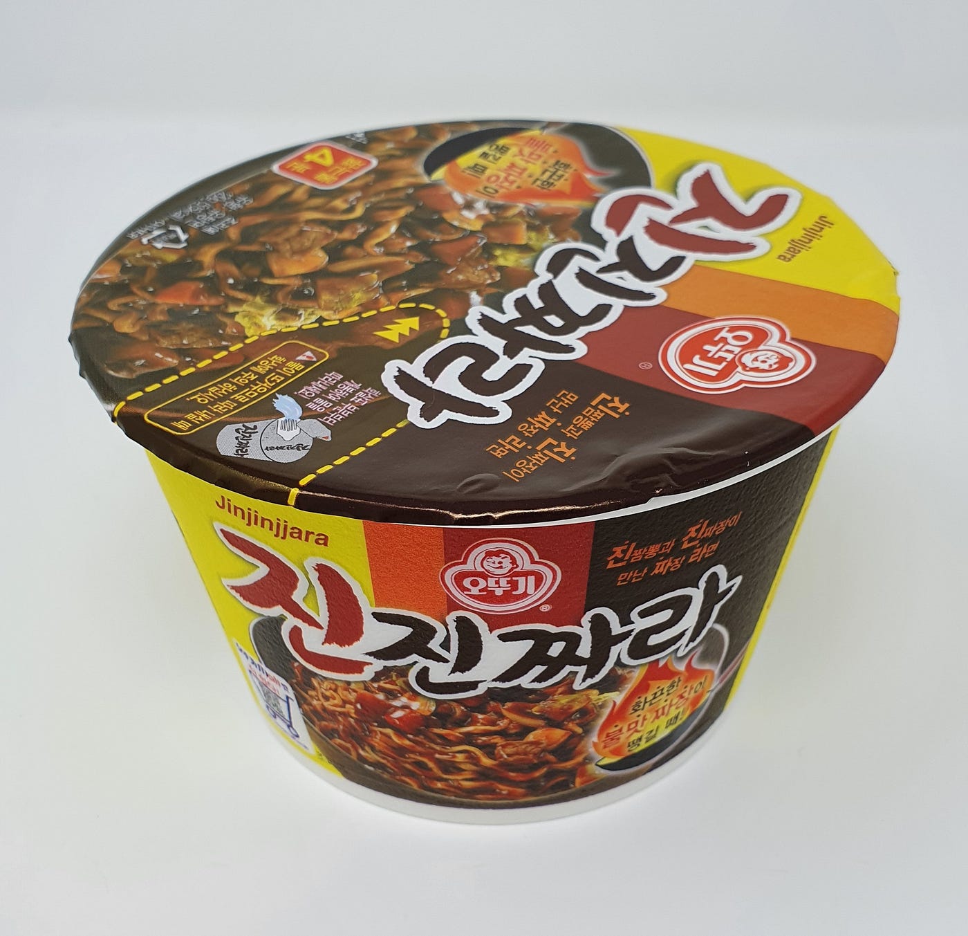 A cup of Ottogi Jinjinjjara Instant Noodles showing the top and front labels.