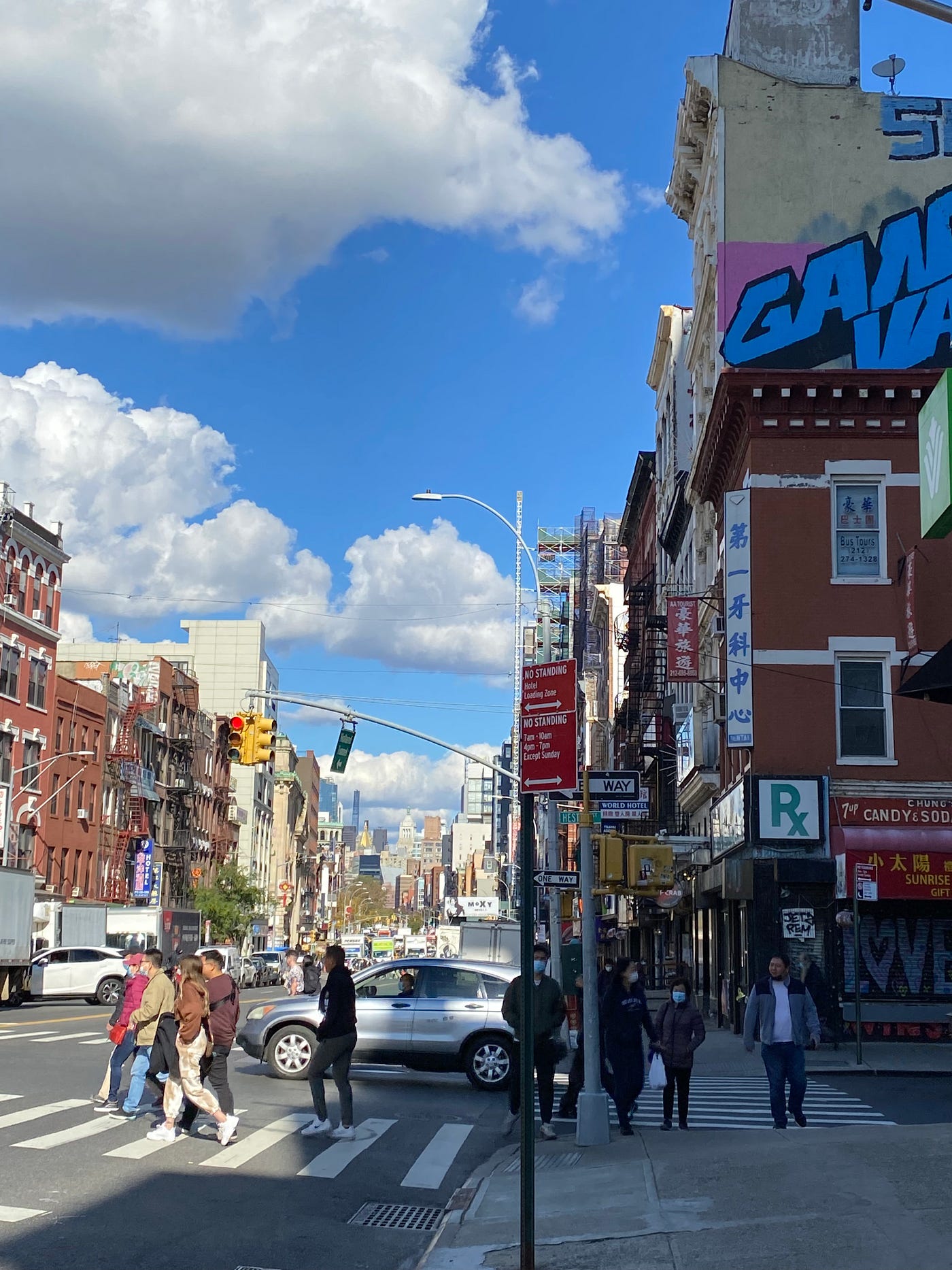 A 2021 photo of buildings in Chinatown with original signage from the 1950s through 1970s save for a Wyndham Gardens Hotel on the right on a beautiful day with clouds in the sky