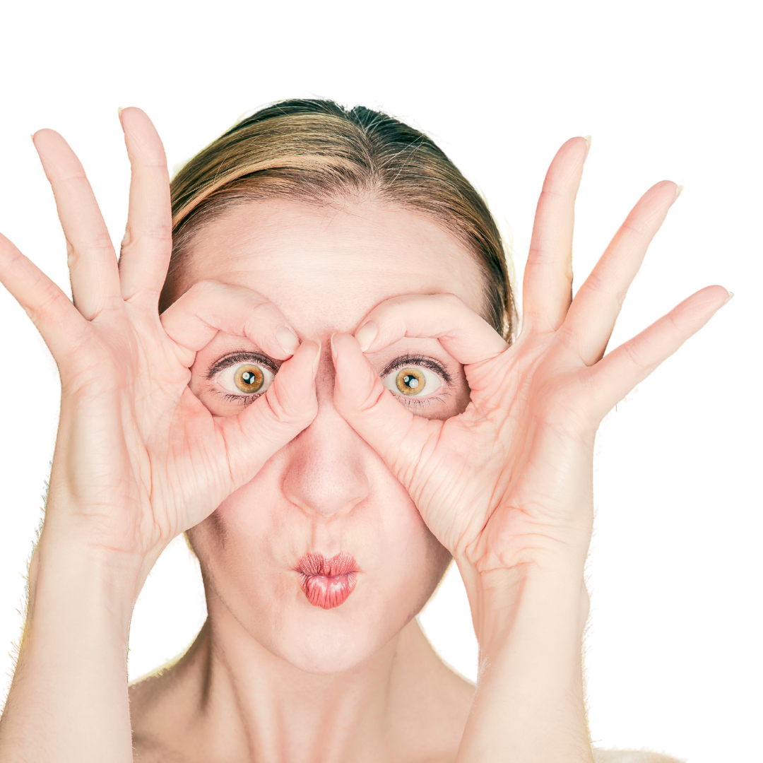 Close-up of woman’s face as she makes imaginary glasses over her eyes with her thumbs and forefingers.
