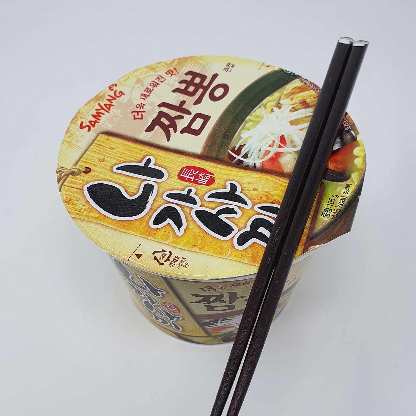 A closed cup of Samyang Nagasaki Jjambbong Instant Noodles cooking for 4 minutes with chopsticks resting on top.