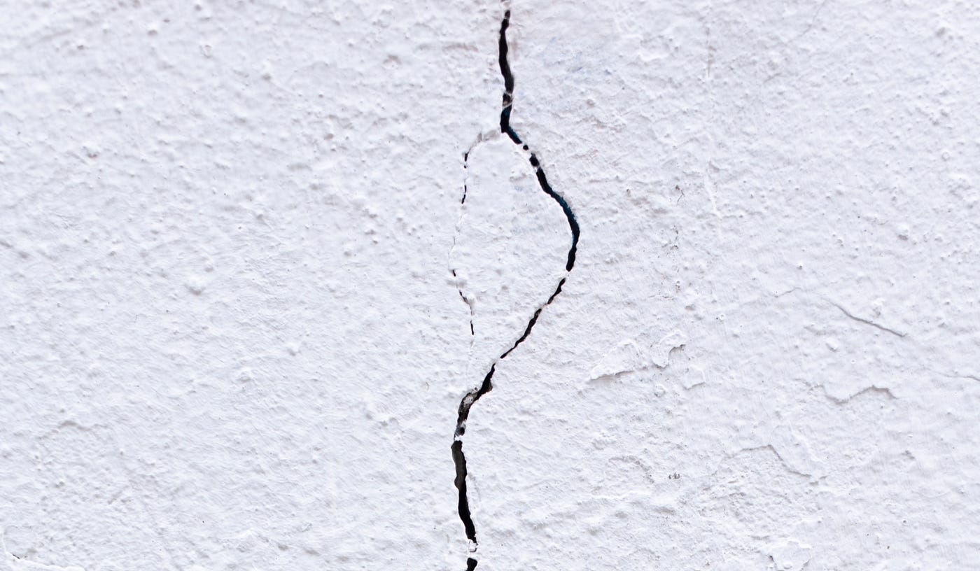 A white stucco wall with a crack down its center.
