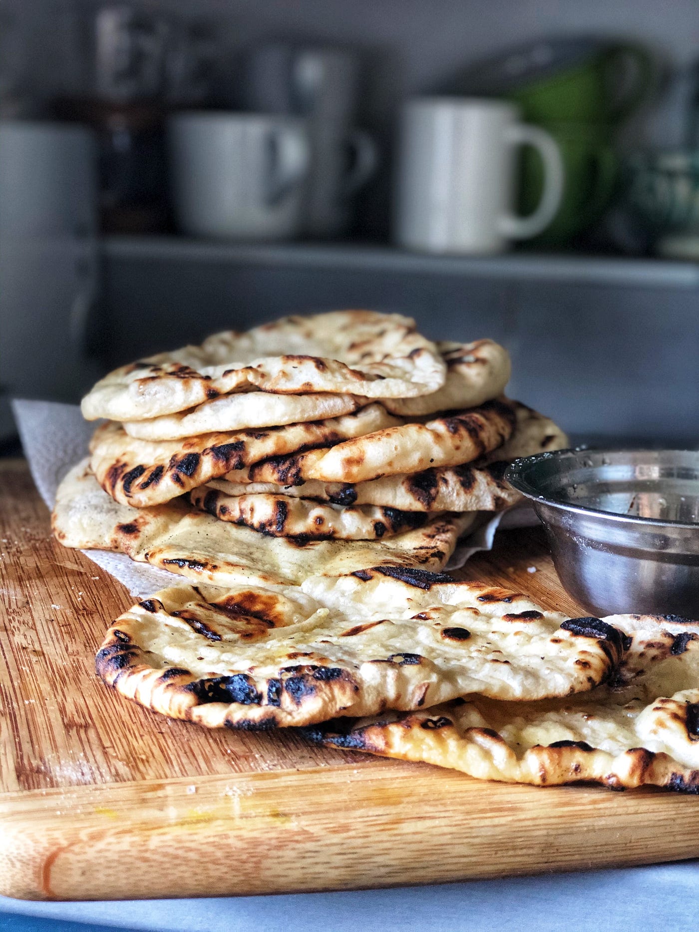A pile of Naan flatbread on a cutting board on the kitchen counter.
