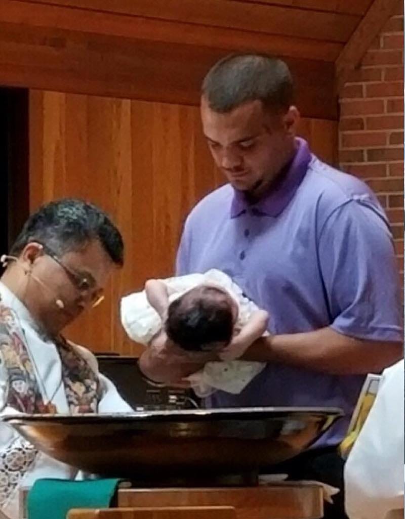 John holding his daughter at her baptism in 2019.