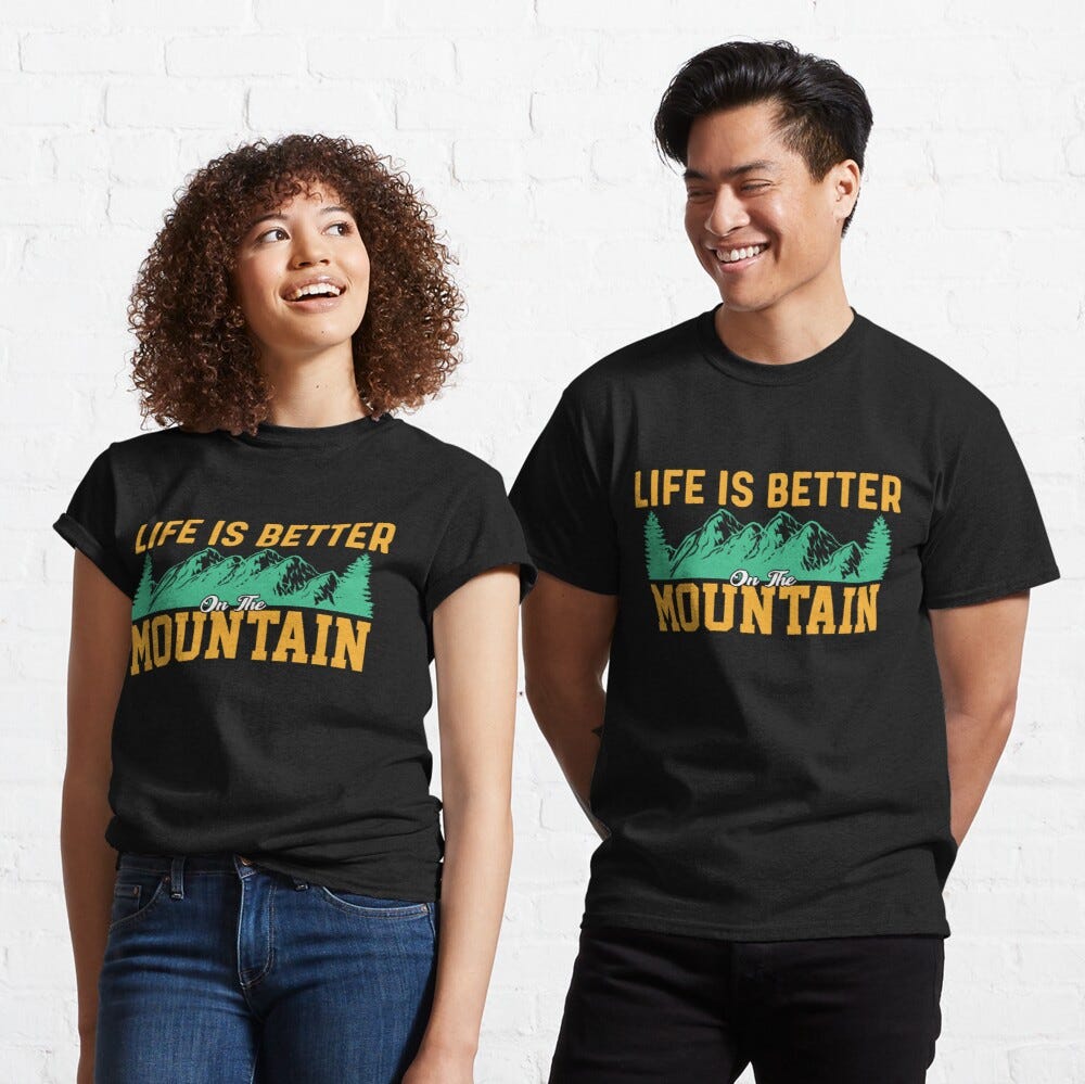 Man and Woman Wearing a black classic t-shirt with amazing illustration and text saying “life is better on the mountain”.