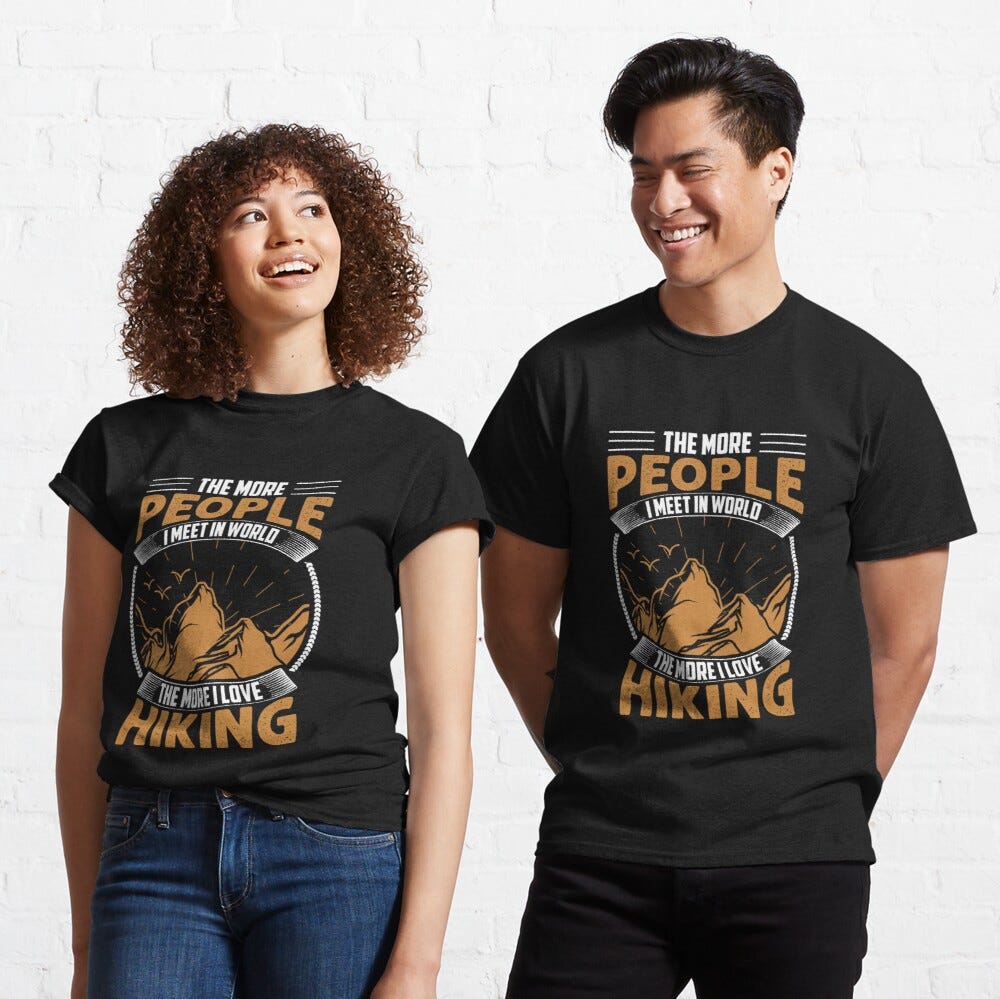 Man and Woman Wearing a black classic t-shirt with amazing illustration and text saying “the more people I meet in the world the more i like hiking”.