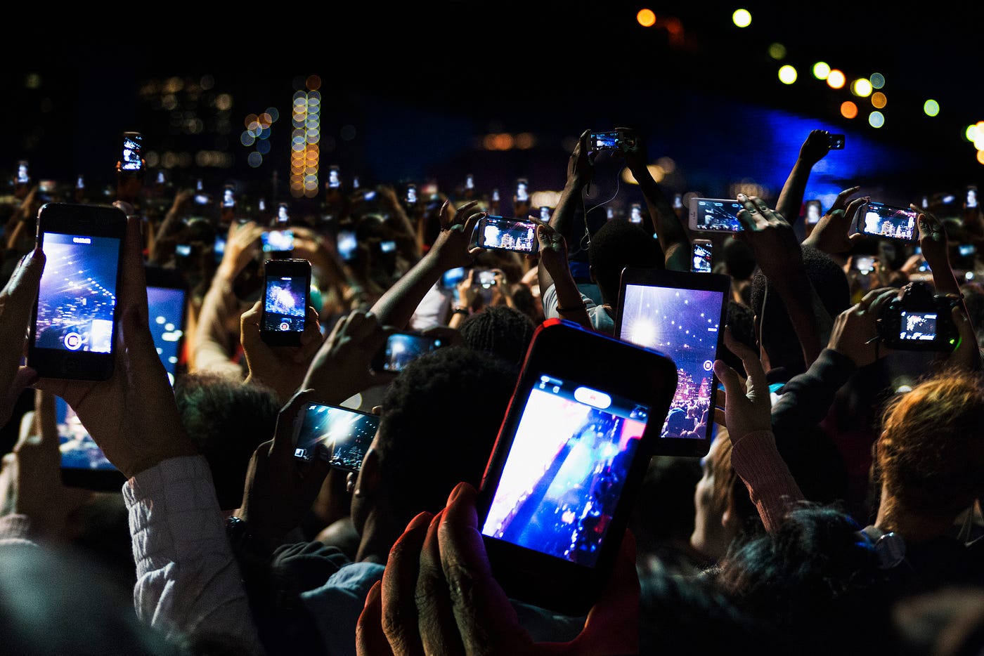 A photo of a sea of phones recording a scene at a concert at night.