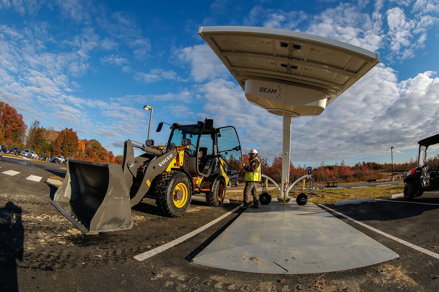 person with small front-end loader next to object with big roof