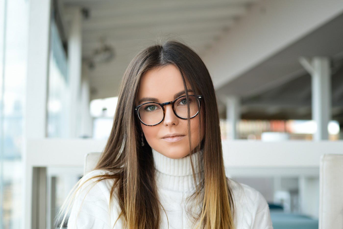 A person wearing glasses and a white sweater.