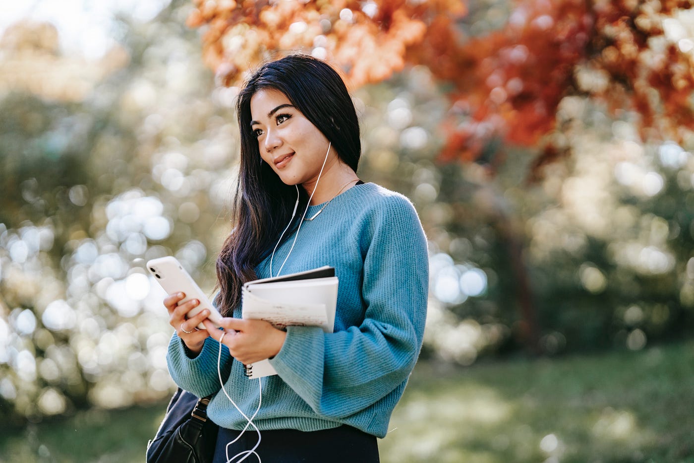 Woman using phone and headphones to audio journal outside