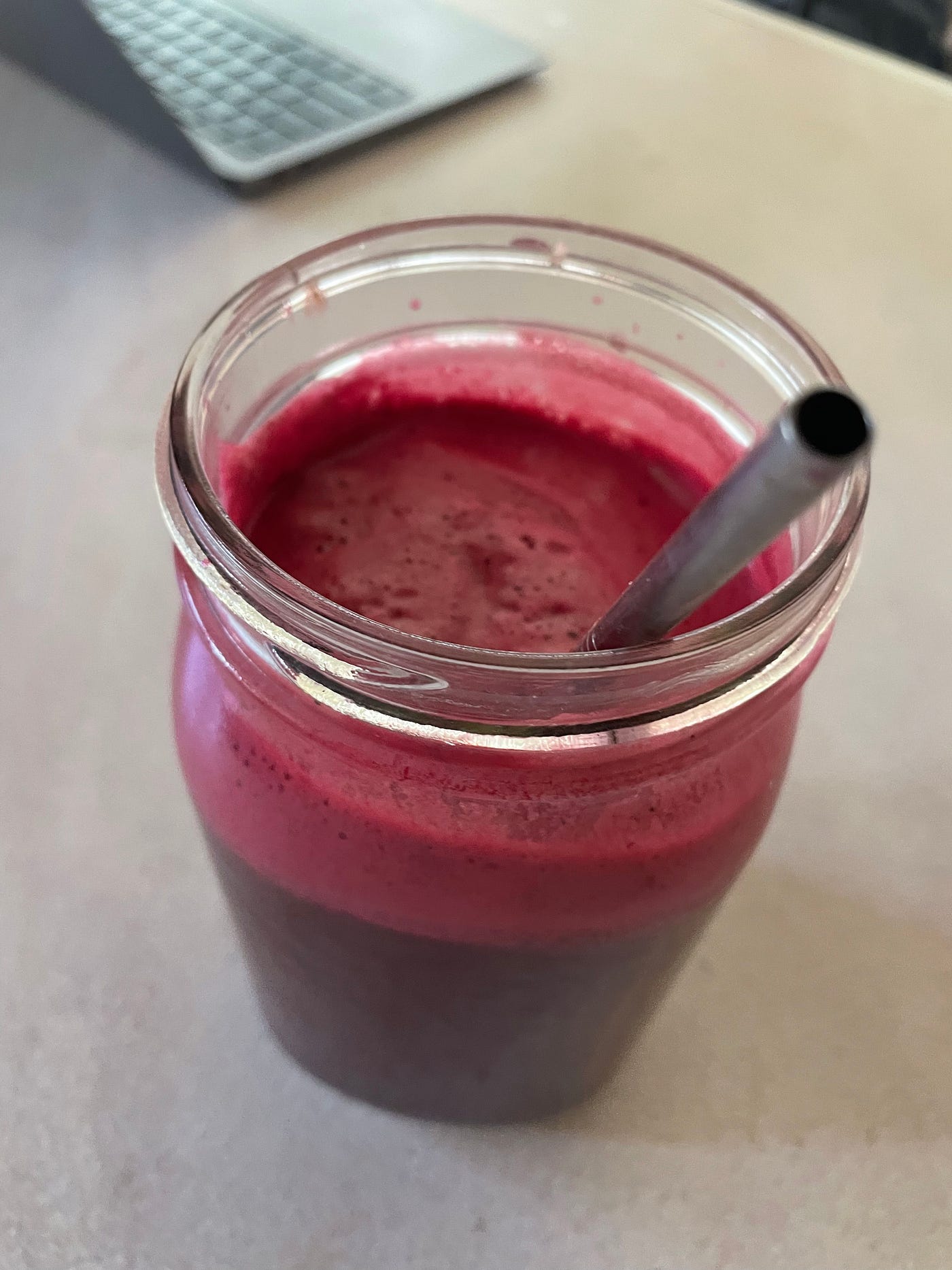 A Glass of fresh beet apple juice with a straw.