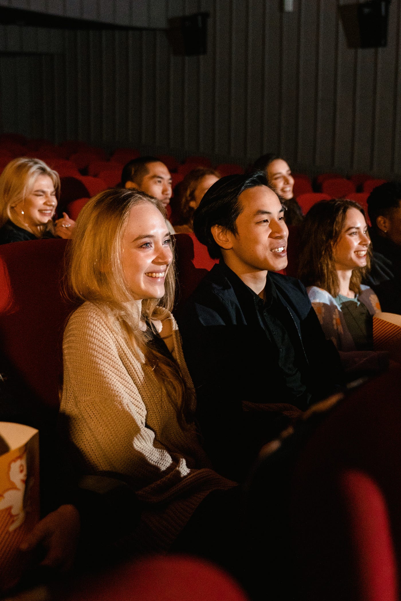 Picture of people smiling while watching a movie in a movie theatre